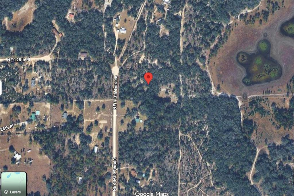 This is a satellite map view showing a red location pin on a wooded lot — 12791 NE 113TH TERRACE, ARCHER, FL