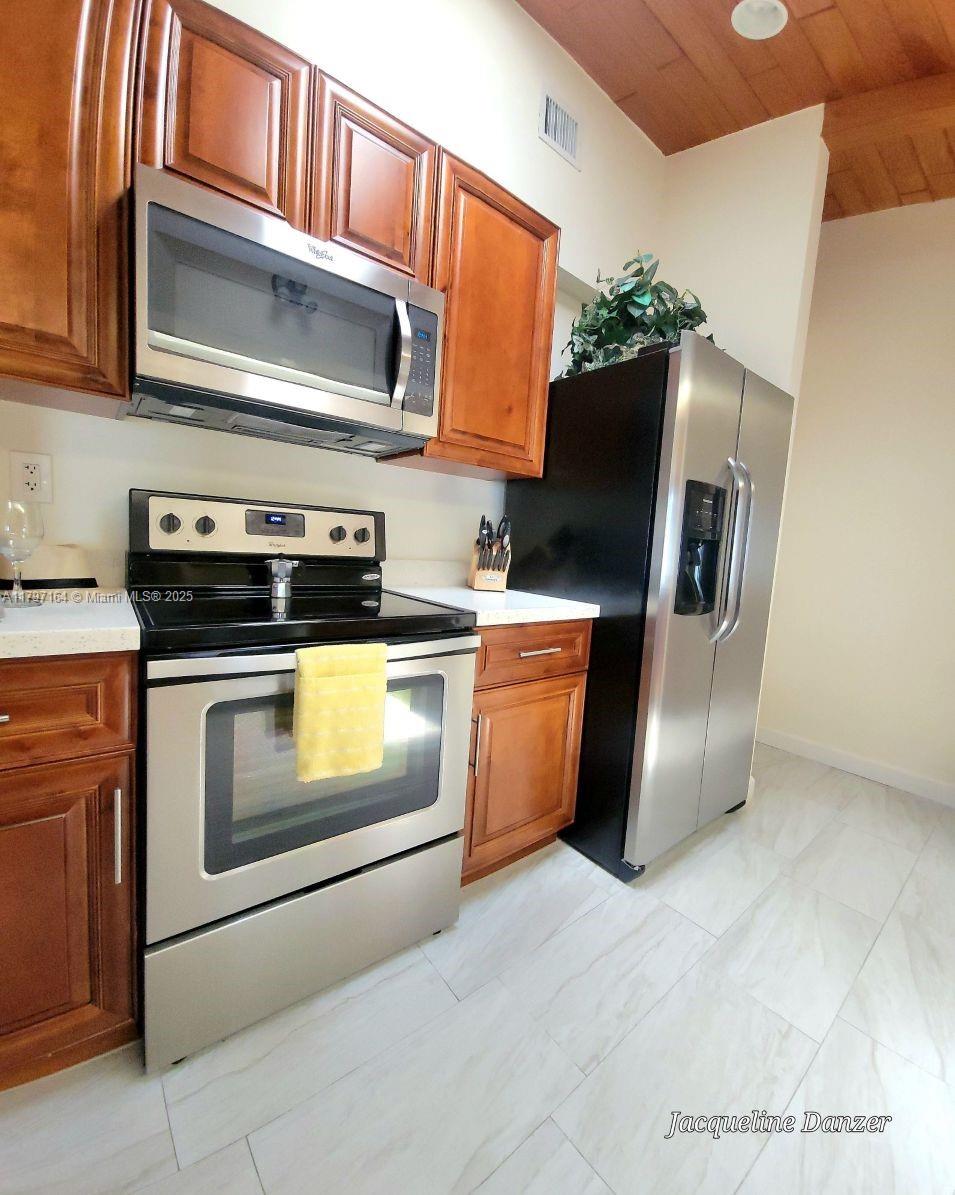 A kitchen features wooden cabinets, stainless steel appliances, and light-colored tile flooring — 2241 NE 38th St # 0, Lighthouse Point FL 33064, LIGHTHOUSE POINT, FL