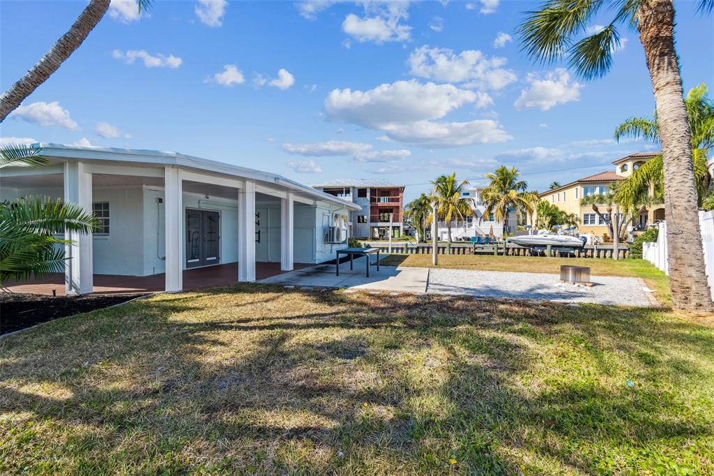 A backyard view of a white house with a covered patio and a gravel area — 1733 BAYOU GRANDE BOULEVARD NE, ST PETERSBURG, FL