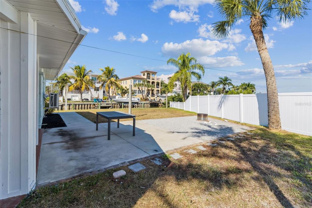 A backyard patio with a table, gravel area, and white fence overlooking a canal — 1733 BAYOU GRANDE BOULEVARD NE, ST PETERSBURG, FL