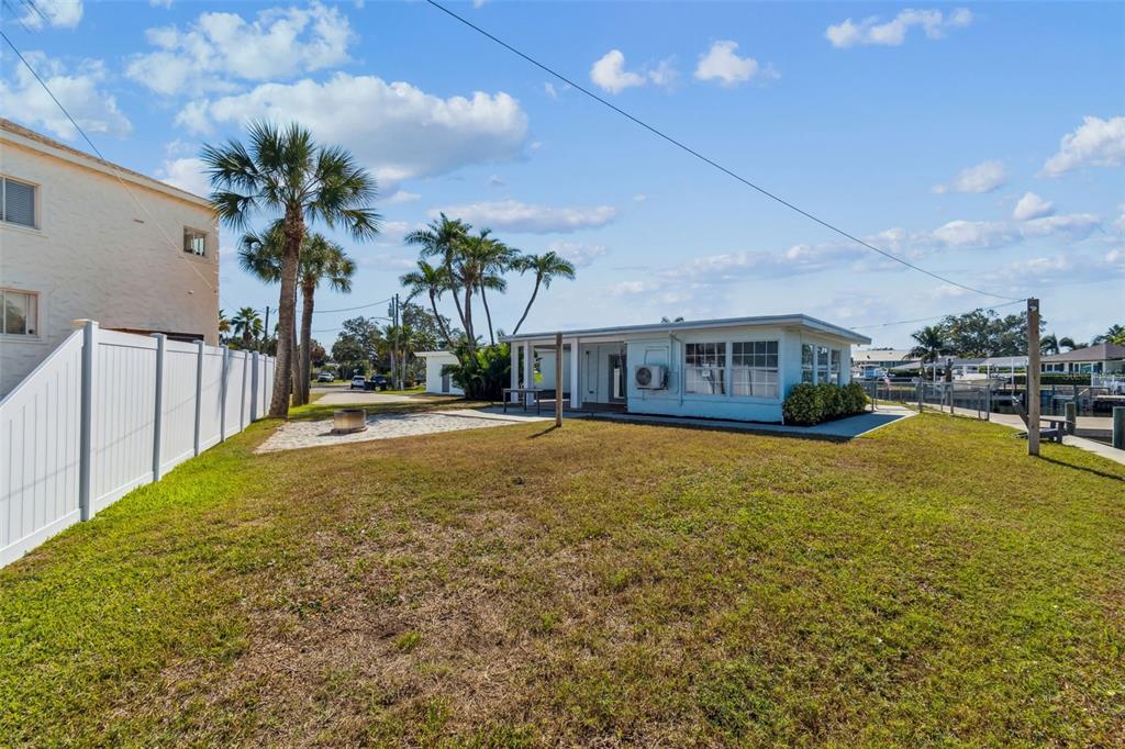 A grassy backyard features a light blue house, palm trees, and a white privacy fence — 1733 BAYOU GRANDE BOULEVARD NE, ST PETERSBURG, FL