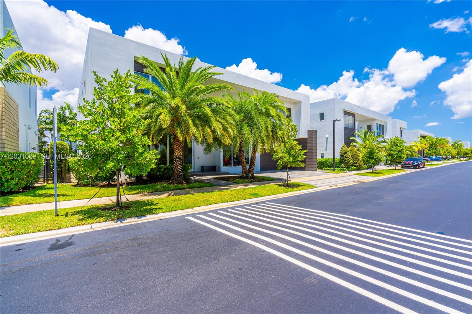 A modern white multi-story residential building features palm trees and a paved street in front — 10267 NW 75th Ter # 10267, Doral FL 33178, DORAL, FL