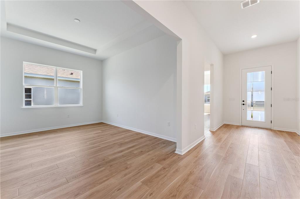A bright room with light wood-look flooring, white walls, and a glass-paneled front door — 1552 SKYLINE HEIGHTS CIRCLE, MINNEOLA, FL