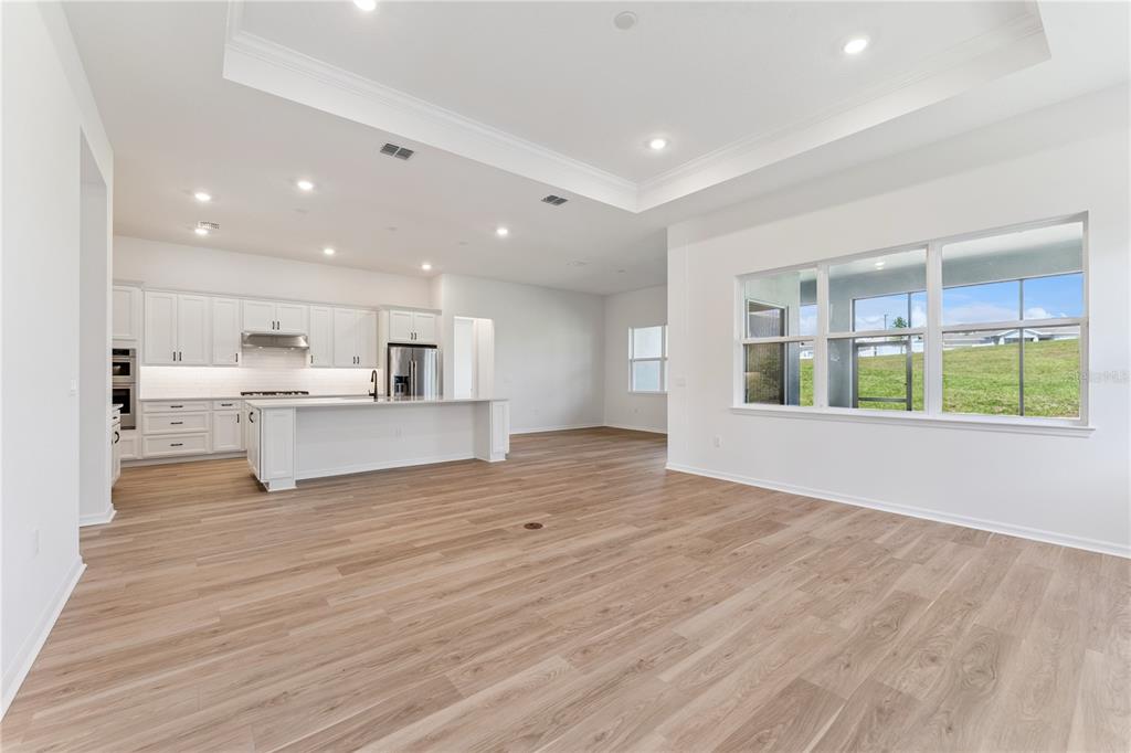 A bright, open-concept kitchen and living area with white cabinetry and light wood flooring — 1552 SKYLINE HEIGHTS CIRCLE, MINNEOLA, FL