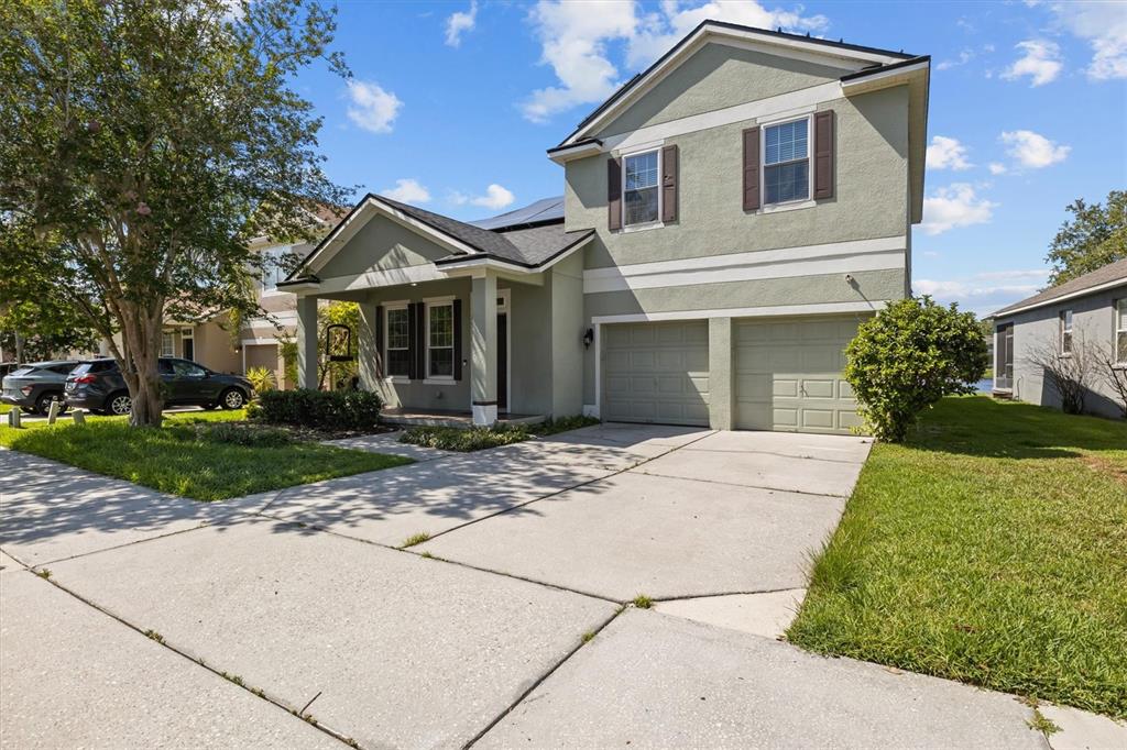 A two-story house with a light green exterior, a two-car garage, and a concrete driveway — 10550 EASTPARK WOODS DRIVE, ORLANDO, FL