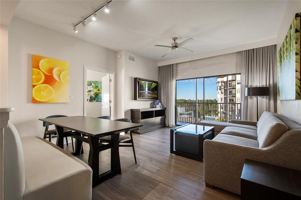 A living and dining area features wood-look flooring, a sofa, a dining table, and balcony access — 14501 GROVE RESORT AVENUE UNIT 2535, WINTER GARDEN, FL