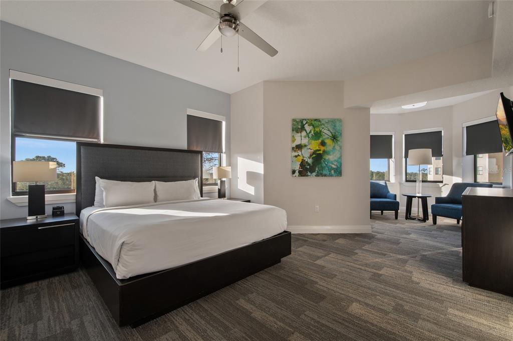 A bedroom features a king bed, gray carpet, and a seating area in a bay window — 14501 GROVE RESORT AVENUE UNIT 2535, WINTER GARDEN, FL