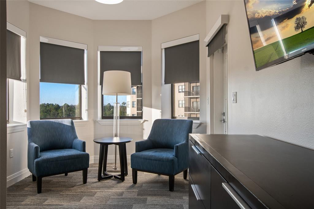 A room with two blue armchairs, a small table, a floor lamp, and large windows — 14501 GROVE RESORT AVENUE UNIT 2535, WINTER GARDEN, FL