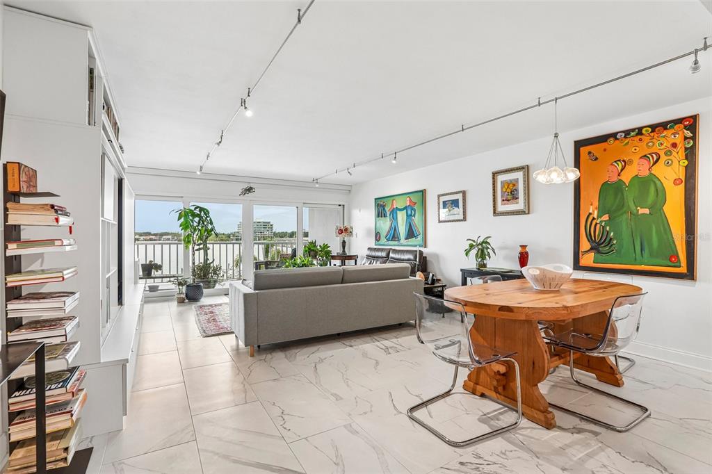 A dining area with a wooden table and clear chairs opens to a living room balcony — 2 ADALIA AVENUE UNIT 301, TAMPA, FL