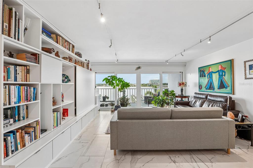 A bright living and dining area features marble-look tile floors, track lighting, and balcony views — 2 ADALIA AVENUE UNIT 301, TAMPA, FL