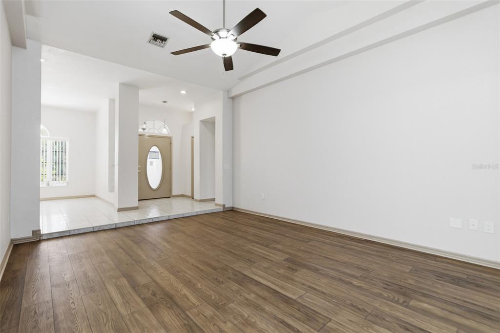 A living room with wood-look flooring, white walls, and a ceiling fan — 191 ROSEMARY STREET, PORT CHARLOTTE, FL