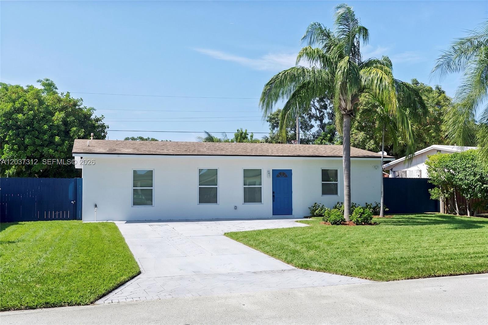 A single-story white house with a blue front door and a palm tree in front — 1473 NE 30th Ct, Pompano Beach FL 33064, POMPANO BEACH, FL