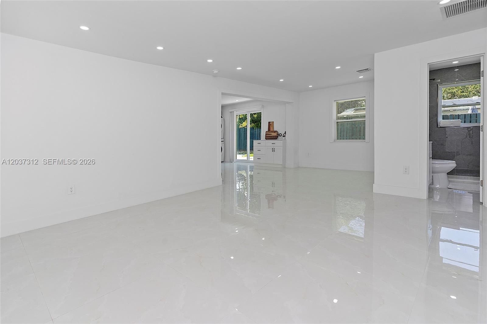 A bright, open-concept living area features white walls, polished tile flooring, and recessed lighting — 1473 NE 30th Ct, Pompano Beach FL 33064, POMPANO BEACH, FL