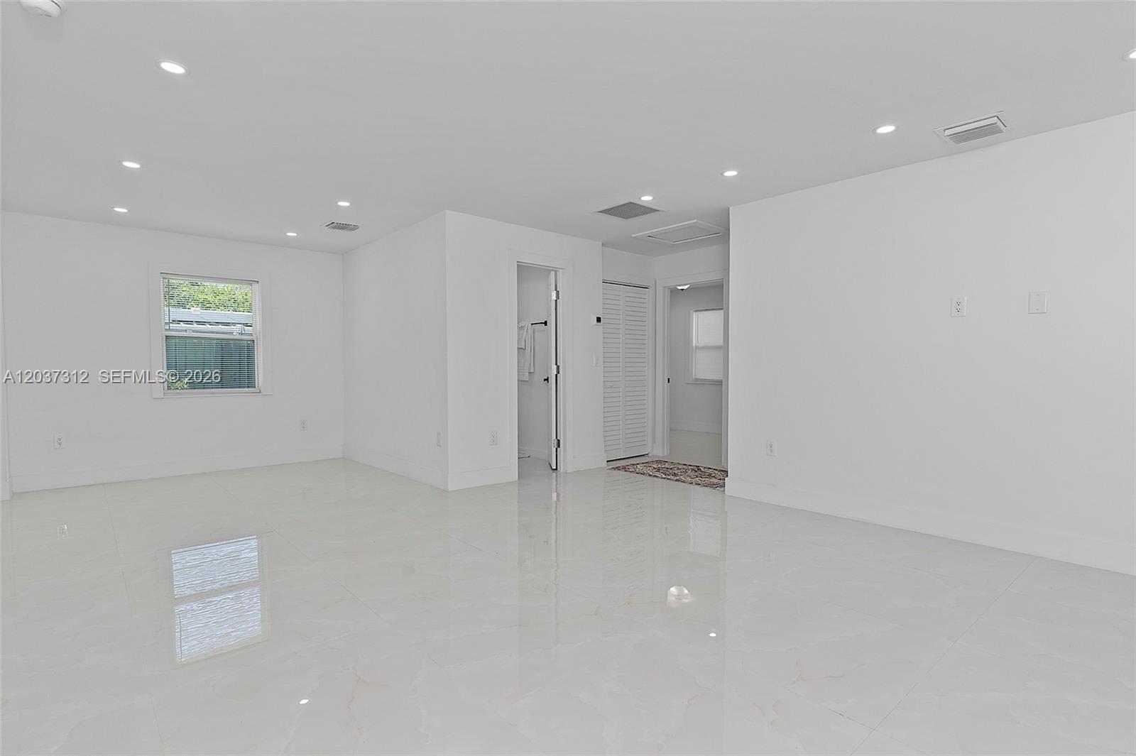A bright, empty room features white walls, recessed lighting, and polished light-colored tile flooring — 1473 NE 30th Ct, Pompano Beach FL 33064, POMPANO BEACH, FL