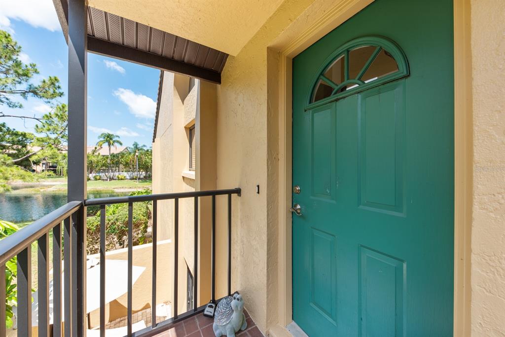 A teal front door with a semi-circular window sits on a balcony overlooking a pond — 5656 ASHTON LAKE DRIVE UNIT 5656, SARASOTA, FL
