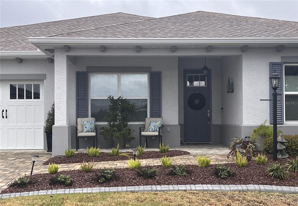 The exterior of a single-story house features a gray facade, a covered porch, and landscaping — 9222 SW 104TH TERRACE, OCALA, FL