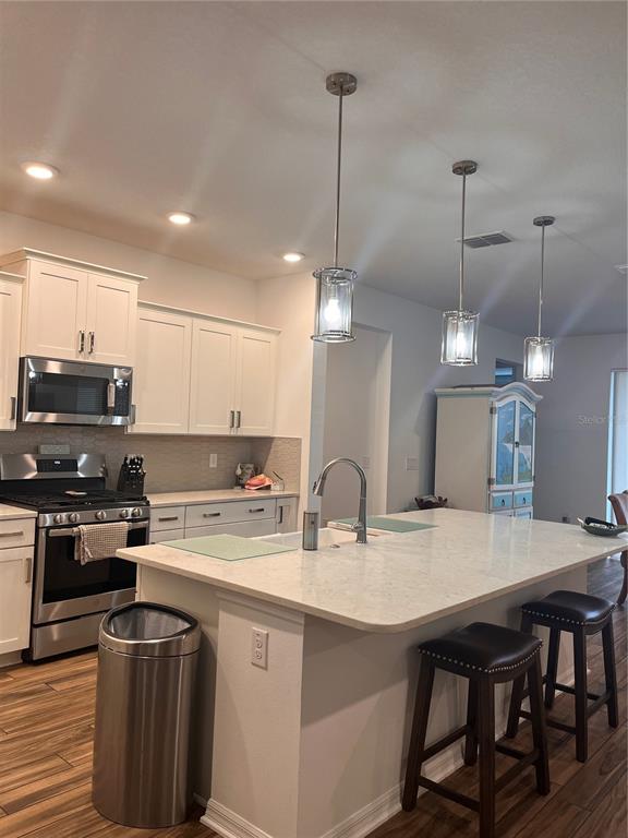 A kitchen features white cabinets, stainless steel appliances, a quartz island, and three pendant lights — 9222 SW 104TH TERRACE, OCALA, FL