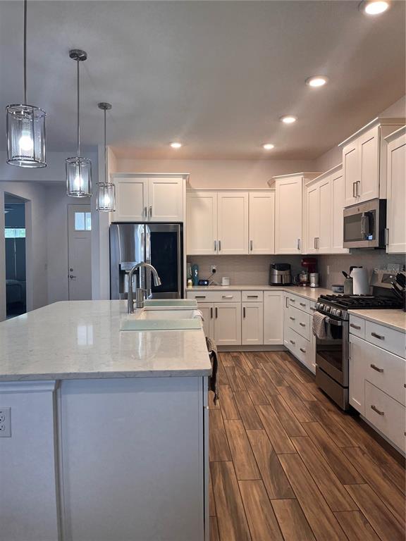 A modern kitchen features white cabinetry, stainless steel appliances, a large island, and wood-look flooring — 9222 SW 104TH TERRACE, OCALA, FL