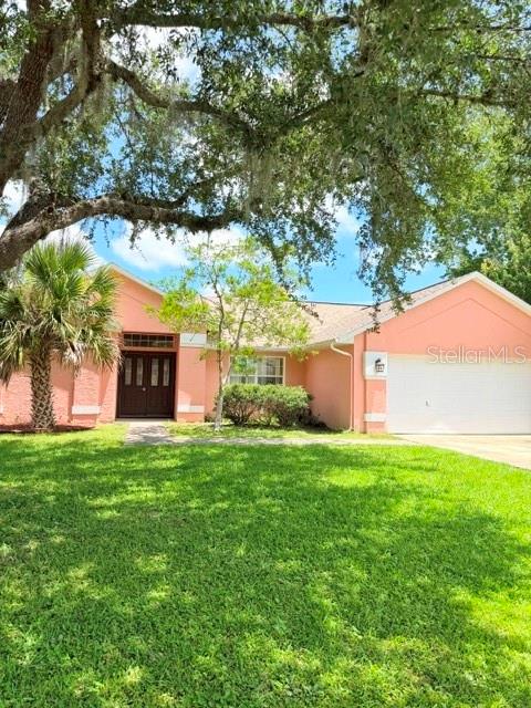 A single-story peach-colored house with a two-car garage and a large oak tree — 20 PALM LANE, PALM COAST, FL