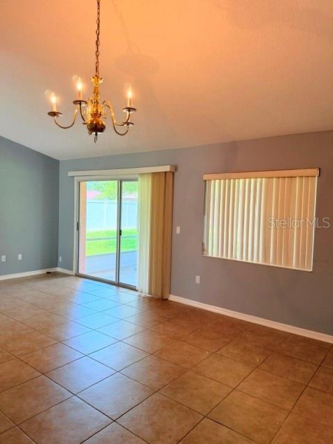A room with tan tile flooring, a chandelier, a sliding glass door, and vertical blinds — 20 PALM LANE, PALM COAST, FL