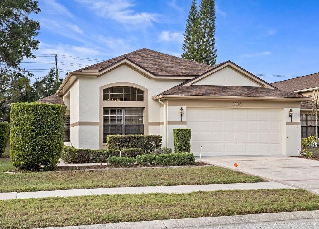 A single-story house with a beige stucco exterior, a two-car garage, and a manicured lawn — 9147 JIMINEZ DRIVE, HUDSON, FL