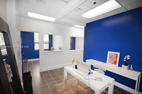 An office space features a white desk, a blue accent wall, and tiled flooring — 168 SE 1st St # 501, Miami FL 33131, MIAMI, FL