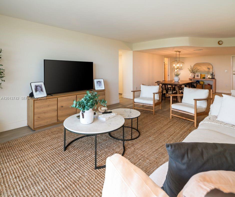 A living room features a wooden media console, two round coffee tables, and white armchairs — KEY BISCAYNE, FL