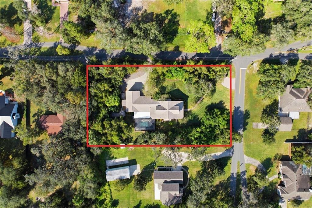 An aerial view shows a house with a pool surrounded by trees and a road — 1190 SUGAR BELT DRIVE, ST CLOUD, FL