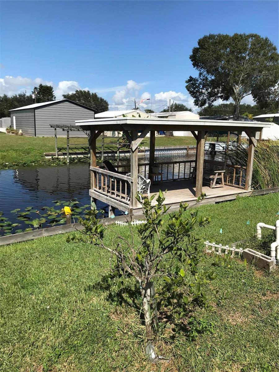 A wooden gazebo sits over a canal next to a small citrus tree and lawn — 1112 21st Street, Okeechobee FL 34974, OKEECHOBEE, FL