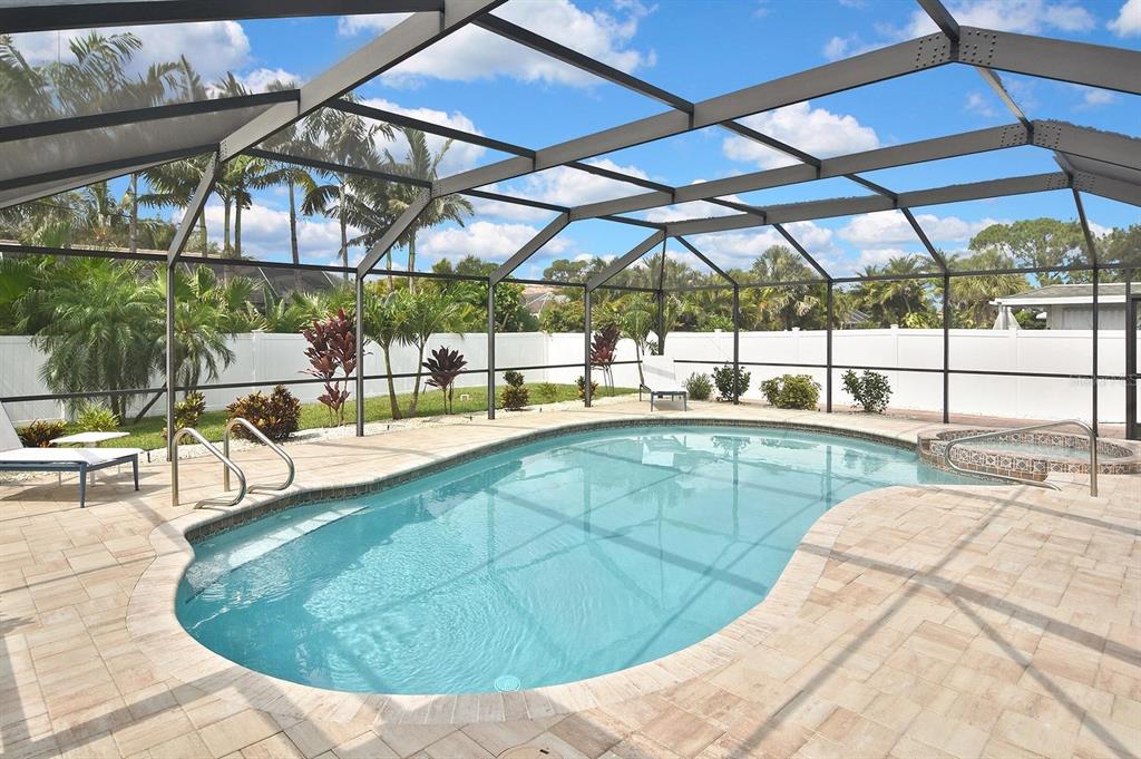 A screened-in swimming pool and hot tub on a paved patio with surrounding palm trees — 429 DARLING DRIVE, VENICE, FL