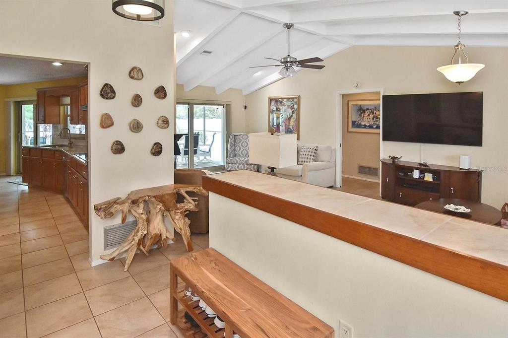 A living room with vaulted ceilings, tile flooring, and a kitchen visible in the background — 429 DARLING DRIVE, VENICE, FL