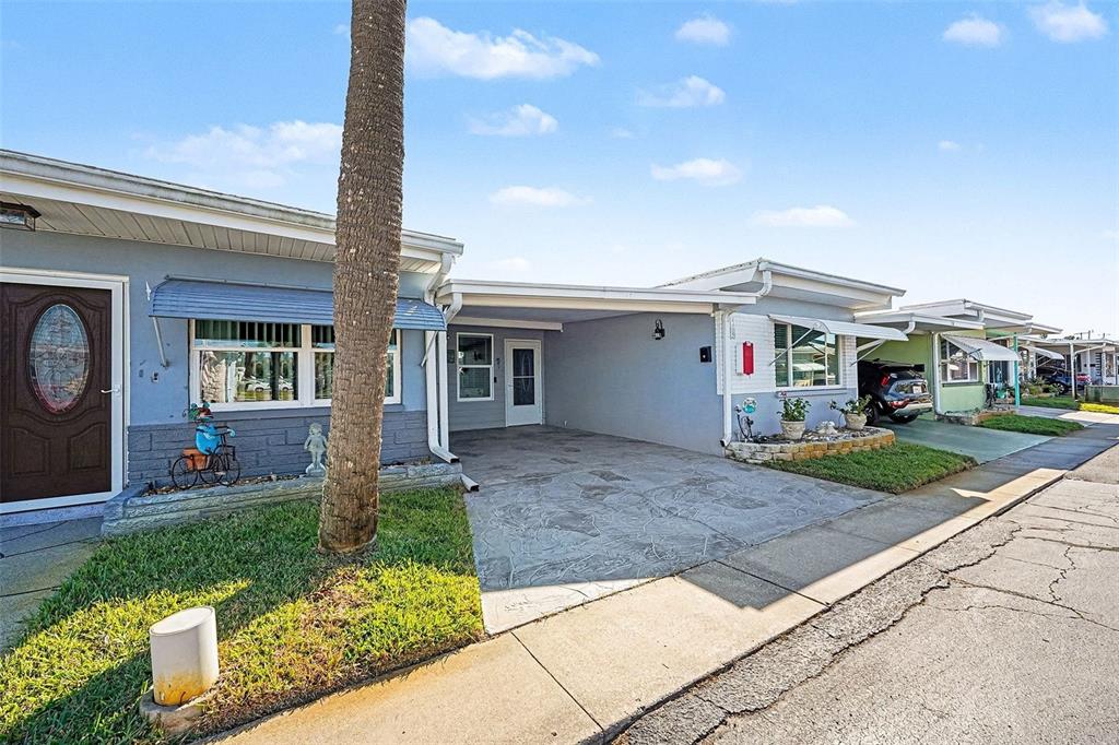A light blue single-story home features a covered carport and a front lawn — 250 ROSERY ROAD NW UNIT 219, LARGO, FL