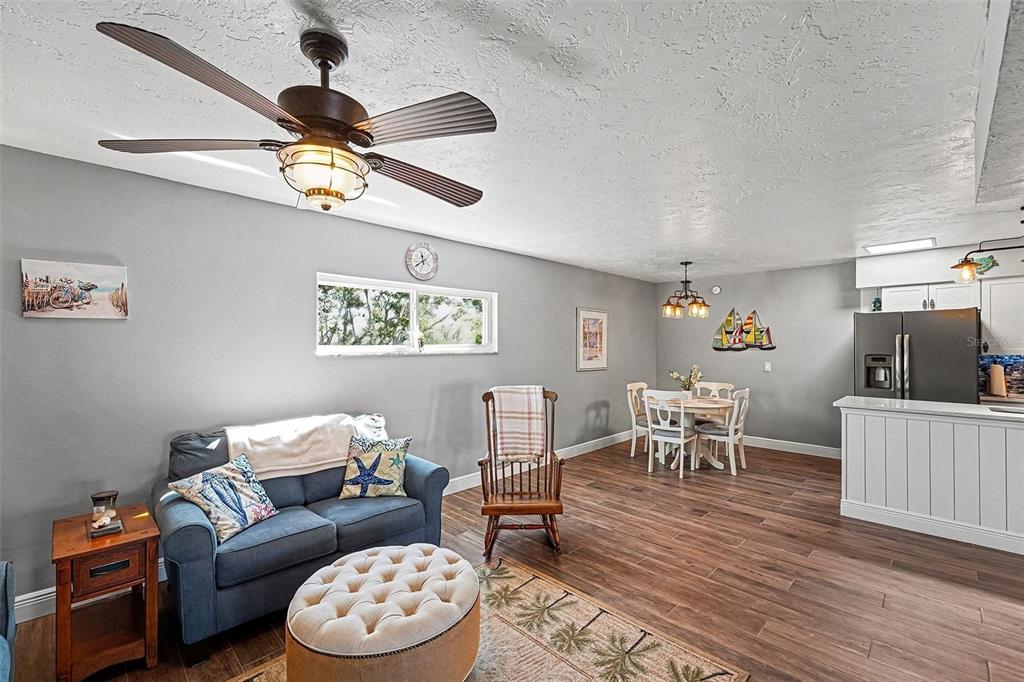 A living and dining area features gray walls, wood-look flooring, and a ceiling fan — 250 ROSERY ROAD NW UNIT 219, LARGO, FL
