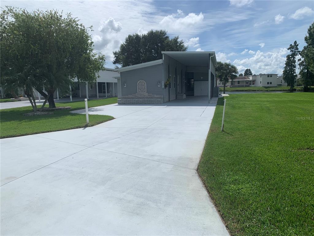 A gray manufactured home features a concrete driveway, a carport, and a grassy yard — 4995 MOUNT OLIVE SHORES DRIVE, POLK CITY, FL