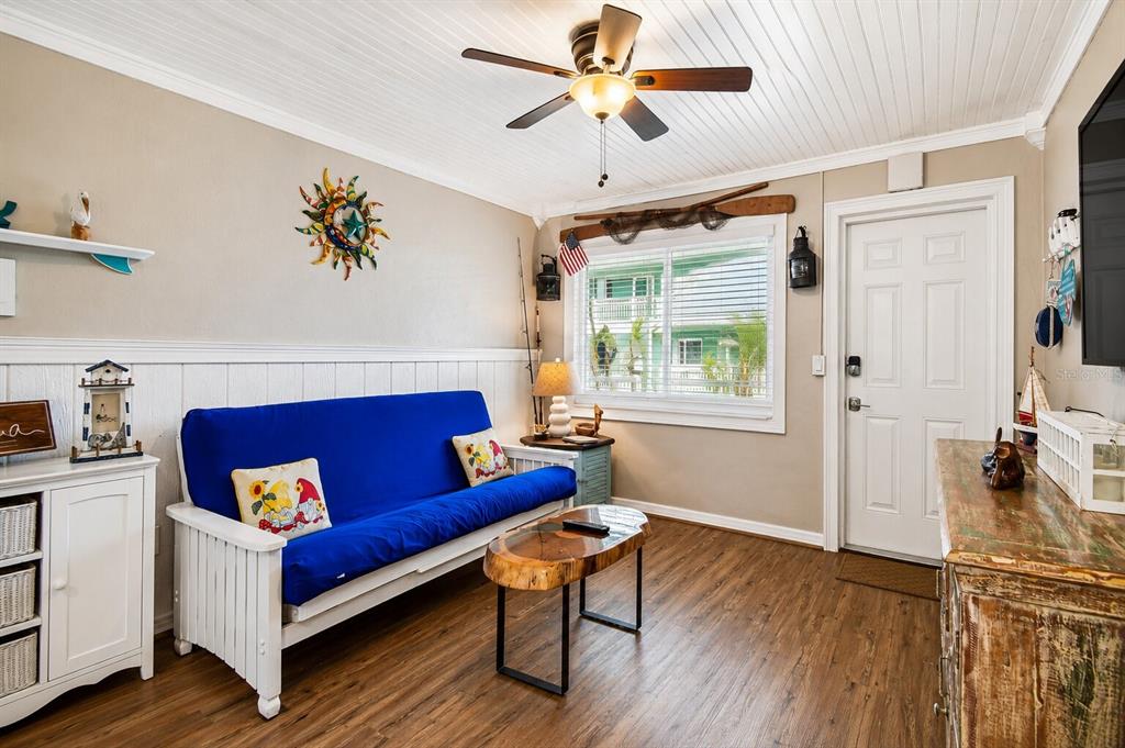 A living room features a blue futon, a live-edge coffee table, and wood-look flooring — 11730 GULF BOULEVARD UNIT 32, ST PETERSBURG, FL