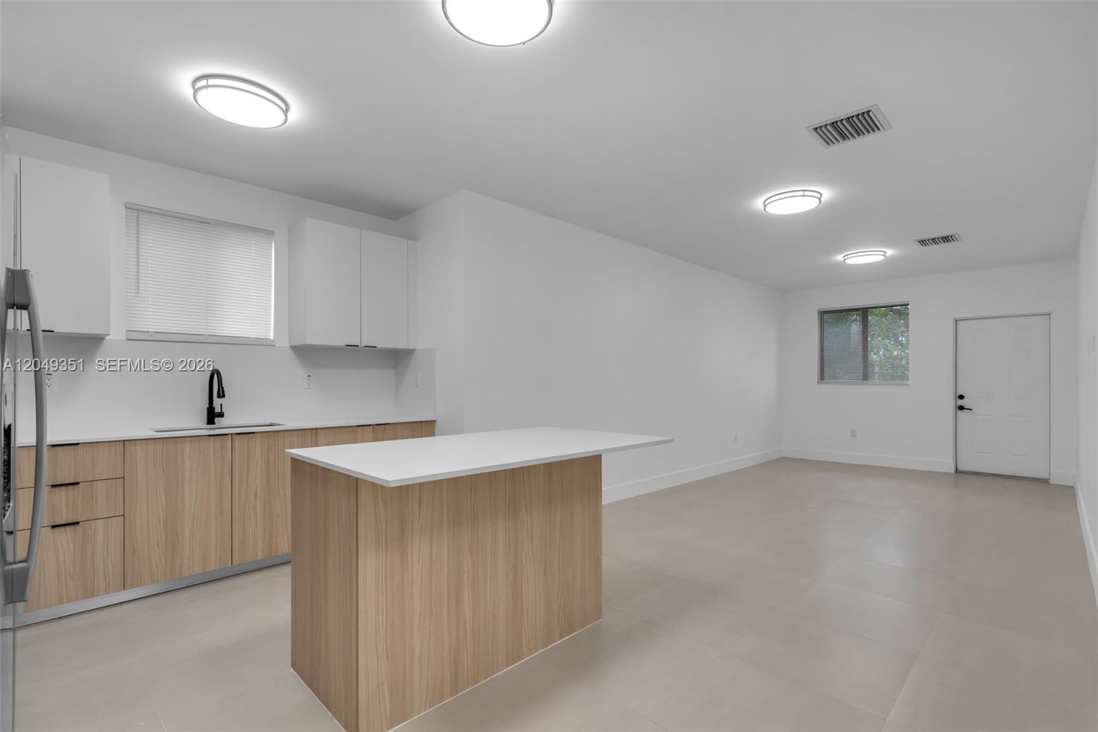 A modern kitchen features light wood cabinets, white countertops, and an island in an open space — 6500 NW 21st Ave # 6500, Miami FL 33147, MIAMI, FL