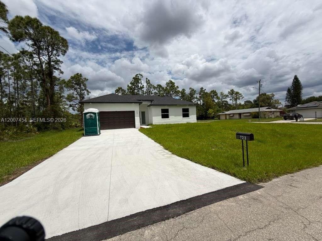 A single-story white house with a dark roof and garage sits on a grassy lot — 723 EPPS BROWN ST E # 723, Lehigh Acres FL 33974, LEHIGH ACRES, FL
