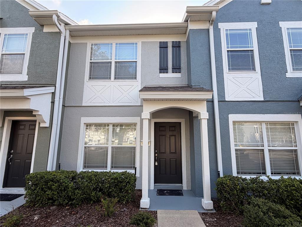 The exterior of a two-story townhouse features gray stucco siding, white trim, and a covered entryway — 4430 SW 49TH AVENUE, OCALA, FL