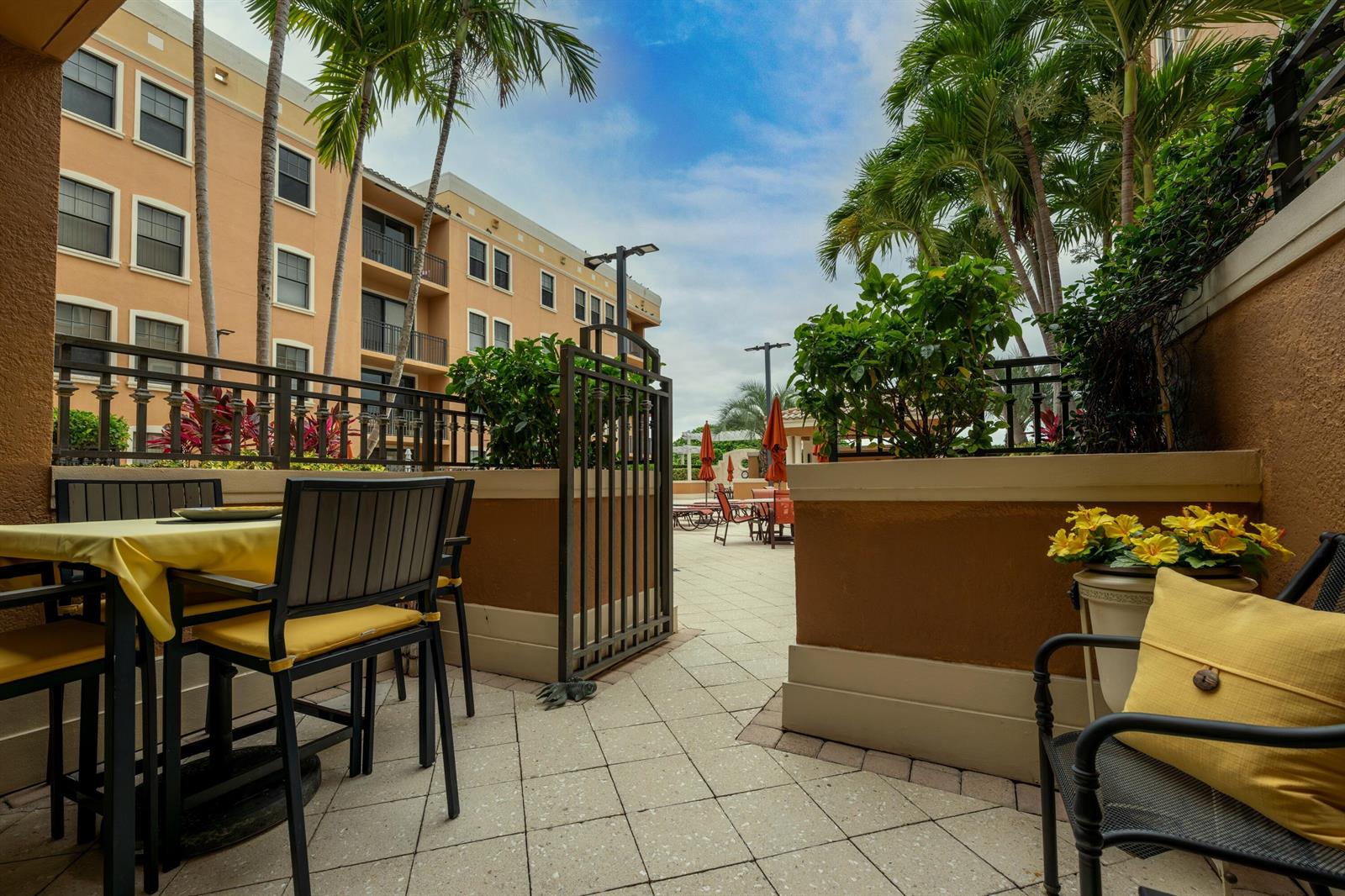 A patio with a dining set and seating area overlooks a pool deck with palm trees — 511 Lucerne Avenue # 312, FL 33460, FL