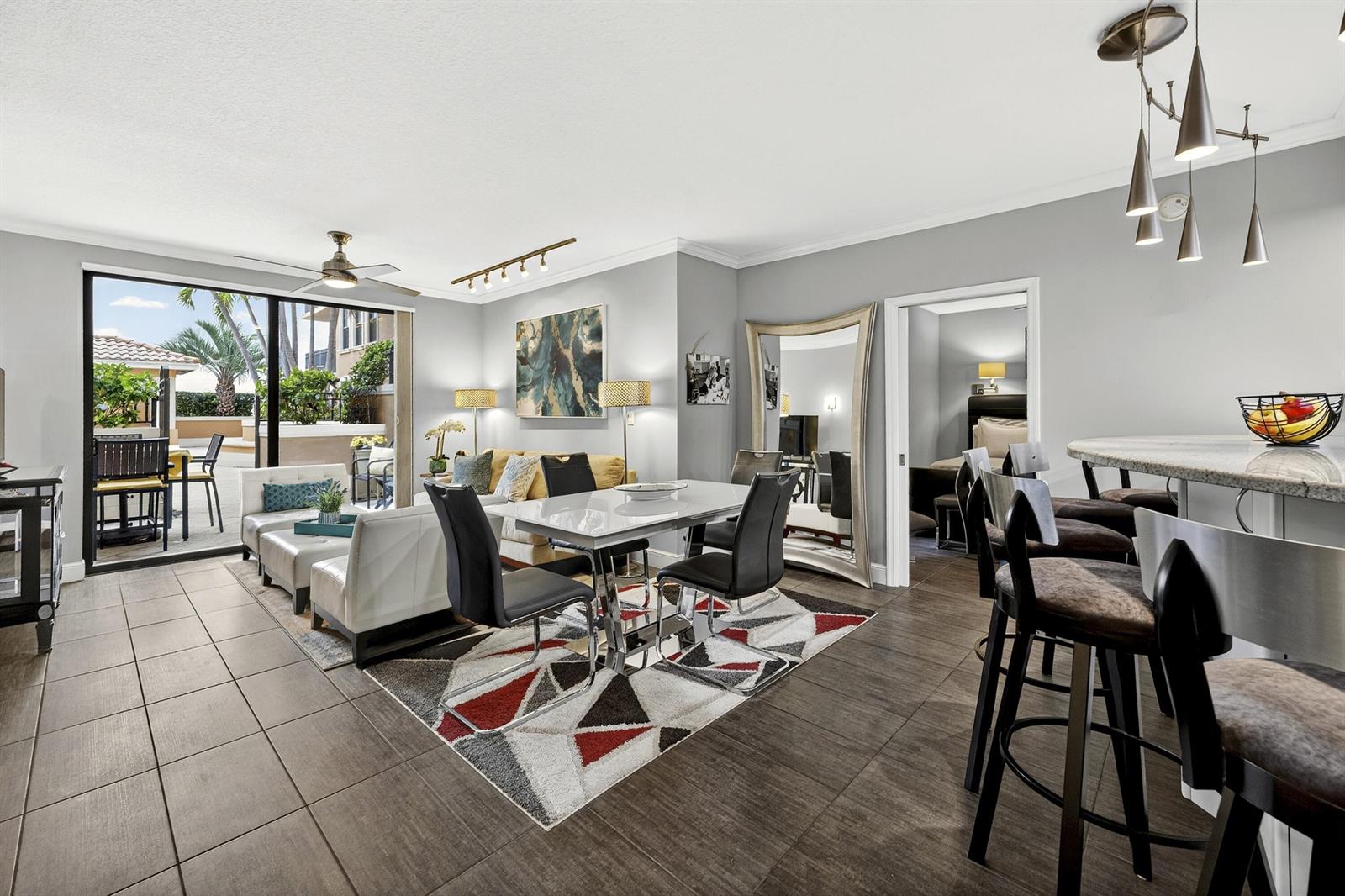 An open-concept living and dining area features tile flooring, modern furniture, and a patio entrance — 511 Lucerne Avenue # 312, FL 33460, FL