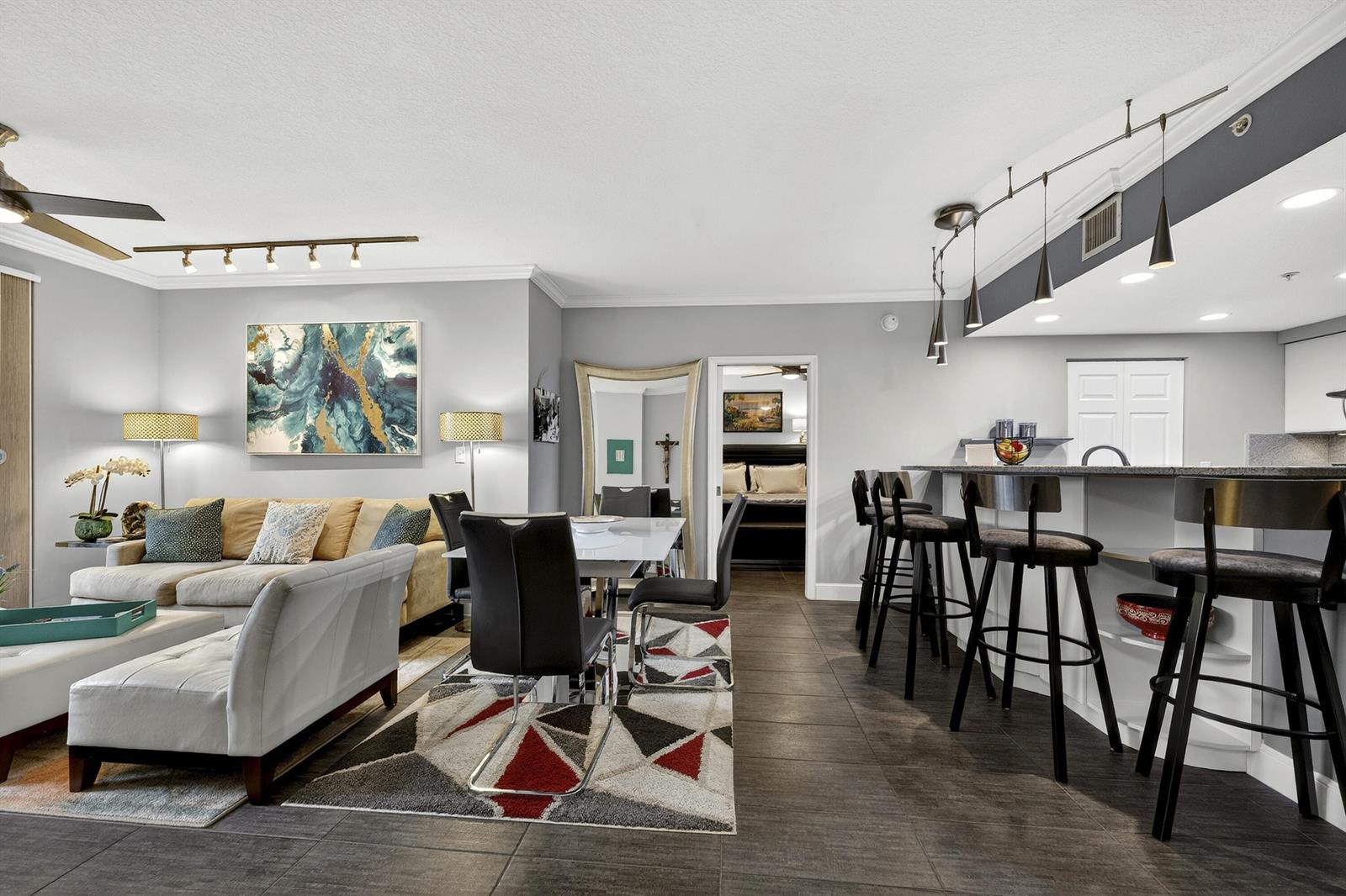 An open-concept living and dining area features tile flooring, a breakfast bar, and modern lighting — 511 Lucerne Avenue # 312, FL 33460, FL