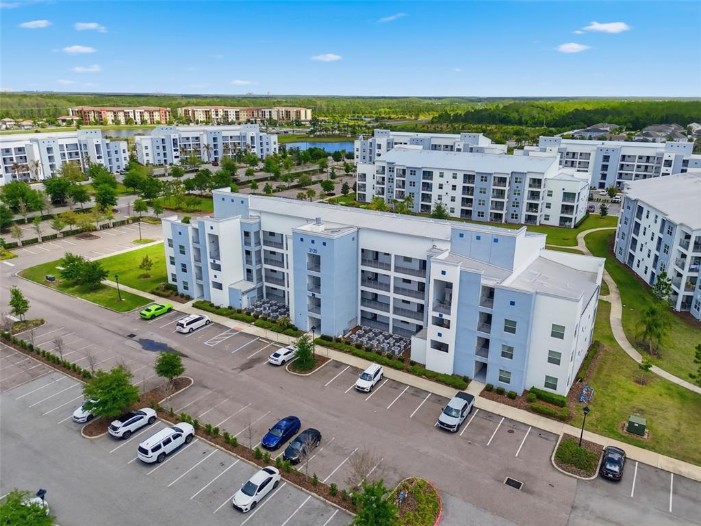 An aerial view shows a multi-story apartment complex with a parking lot in front — 3120 PARADOX CIRCLE UNIT 302, KISSIMMEE, FL