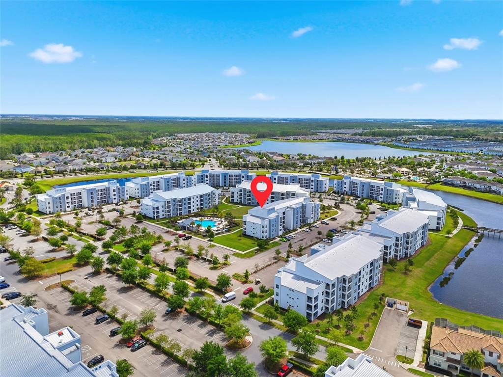 An aerial view shows a multi-story apartment complex with a pool and surrounding parking lots — 3120 PARADOX CIRCLE UNIT 302, KISSIMMEE, FL