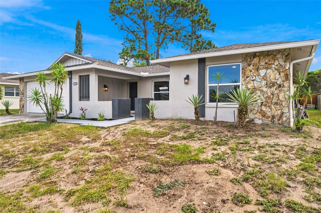 A single-story house with a stone facade, a covered entryway, and a patchy dirt lawn — 8022 IDLEBRIAR LANE, PORT RICHEY, FL