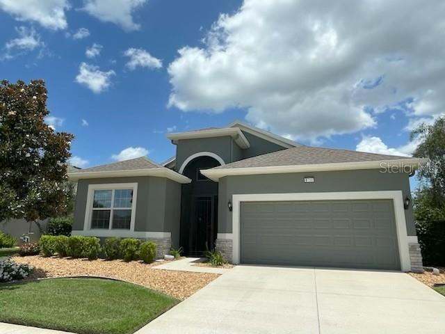 A gray single-story house with a two-car garage and a landscaped front yard — 8716 BRIDGEPORT BAY CIRCLE, MOUNT DORA, FL
