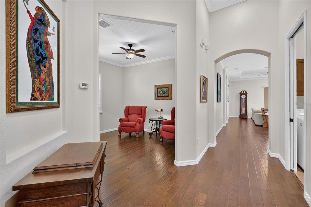A hallway with hardwood floors leads to a living area with two red armchairs — 8716 BRIDGEPORT BAY CIRCLE, MOUNT DORA, FL