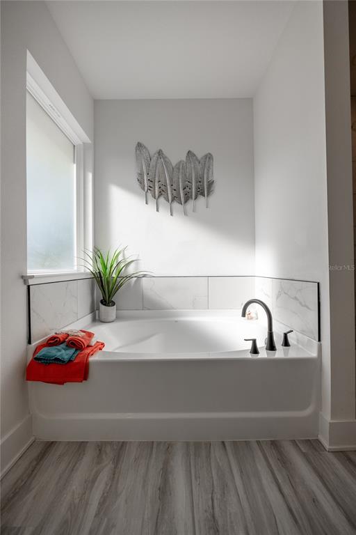 A white soaking tub with a dark faucet sits in a bathroom with tiled walls — 17766 NW 168TH ROAD, ALACHUA, FL