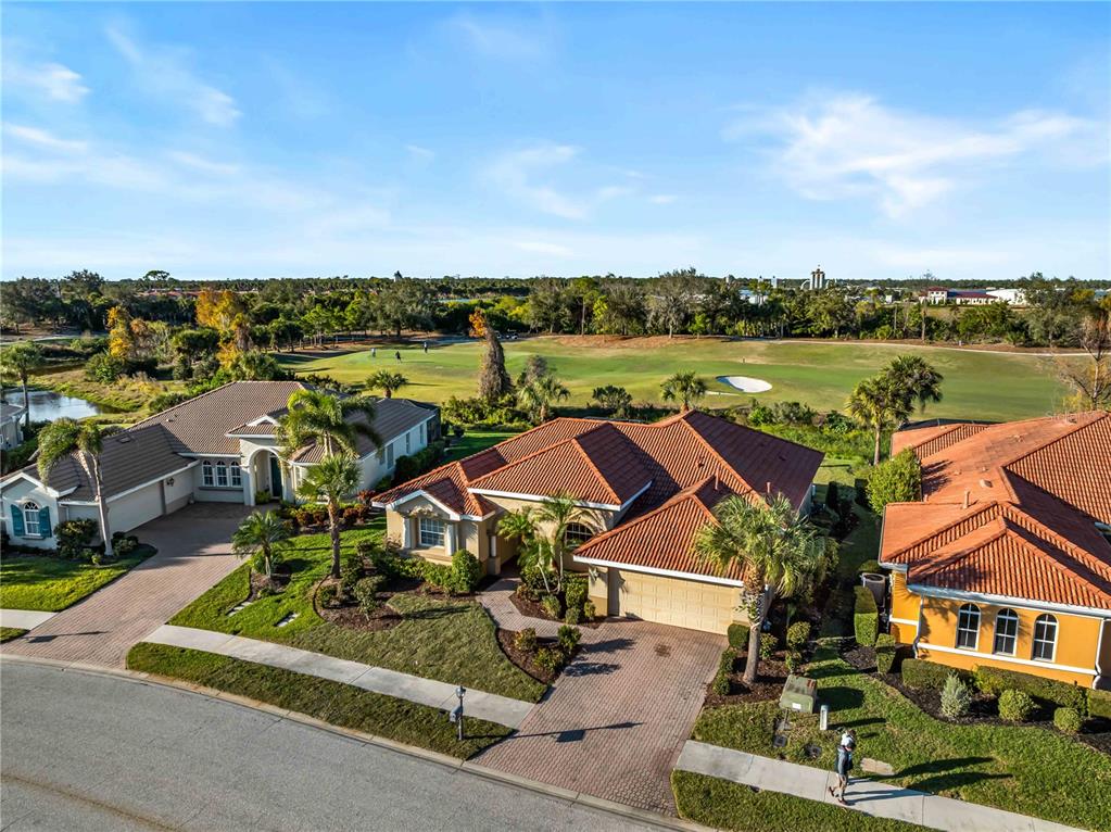 An aerial view shows three suburban houses with tile roofs overlooking a golf course — 274 MONTELLUNA DRIVE, NORTH VENICE, FL