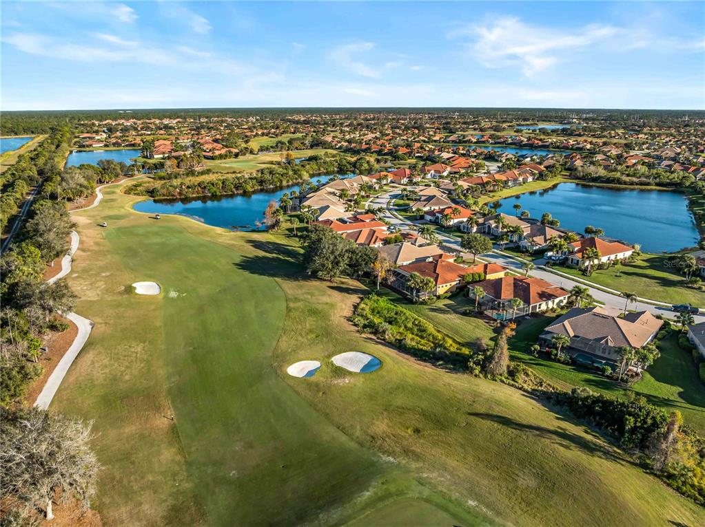 An aerial view shows a golf course fairway adjacent to a residential neighborhood with lakes — 274 MONTELLUNA DRIVE, NORTH VENICE, FL
