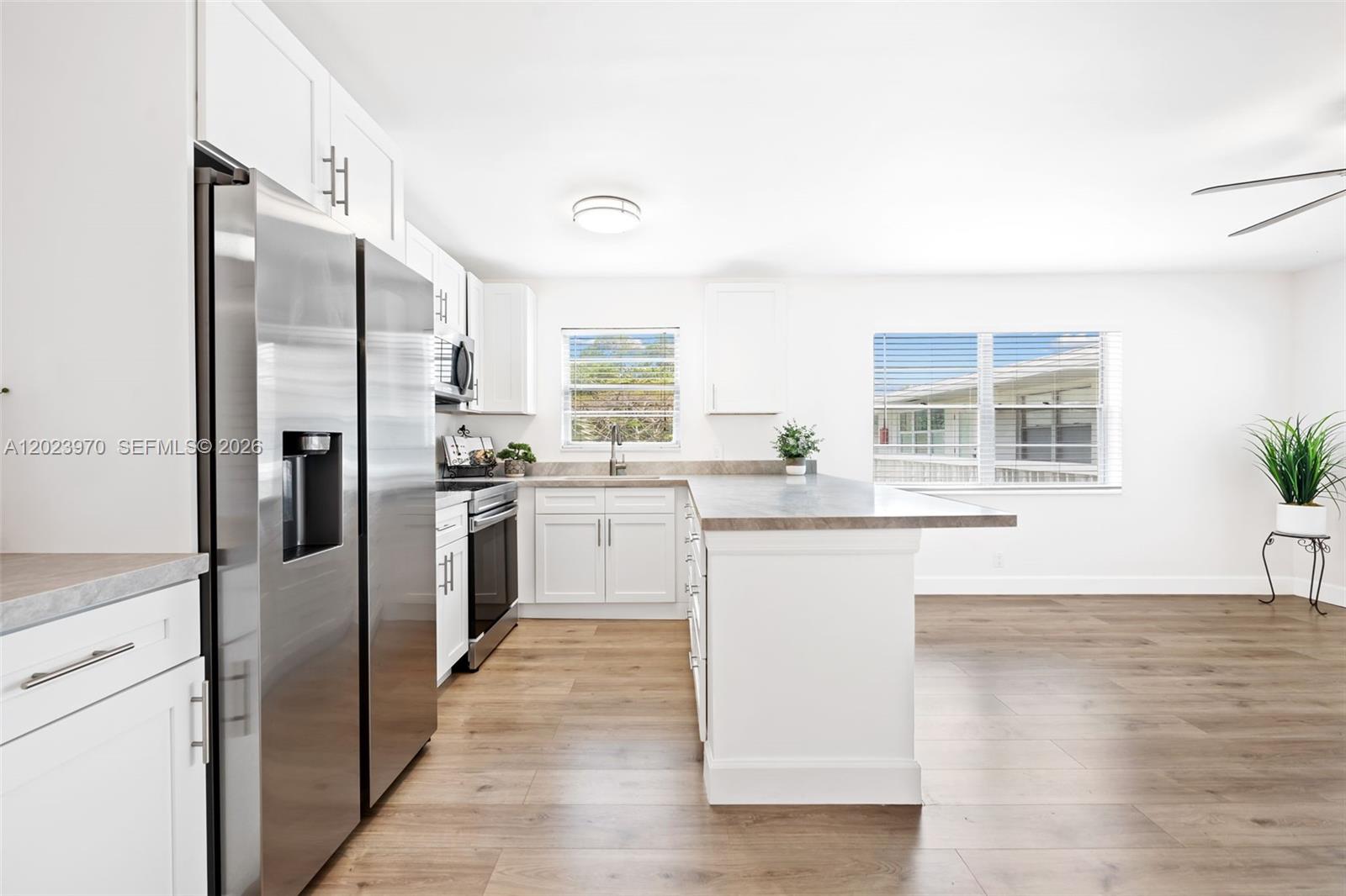 A modern kitchen features white cabinets, stainless steel appliances, and a central island — 17 Lyndhurst # A, Deerfield Beach FL 33442, DEERFIELD BEACH, FL